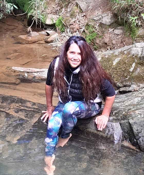 Sol, founder and QHHT practitioner, sitting by a creek